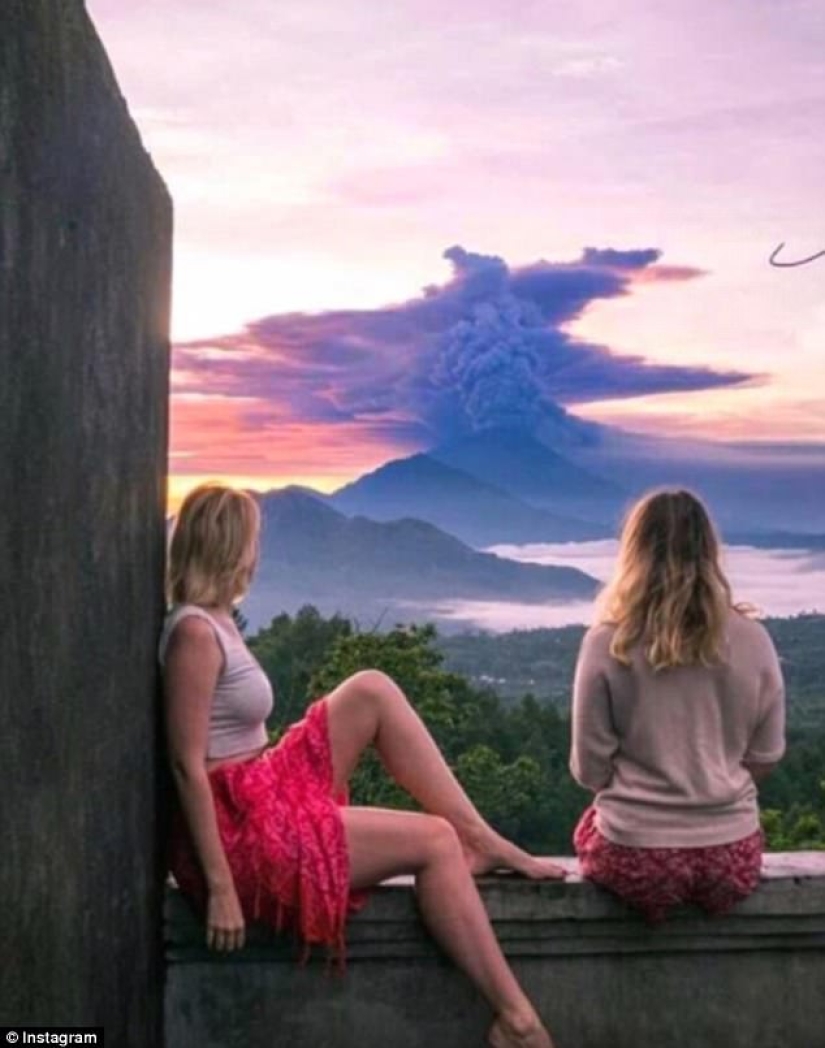 Mientras los residentes de Bali se alejan del volcán, los turistas son fotografiados con el telón de fondo de las emisiones de cenizas Mientras los residentes de Bali se alejan del volcán, los turistas son fotografiados con el telón de fondo de las emisiones de cenizas
