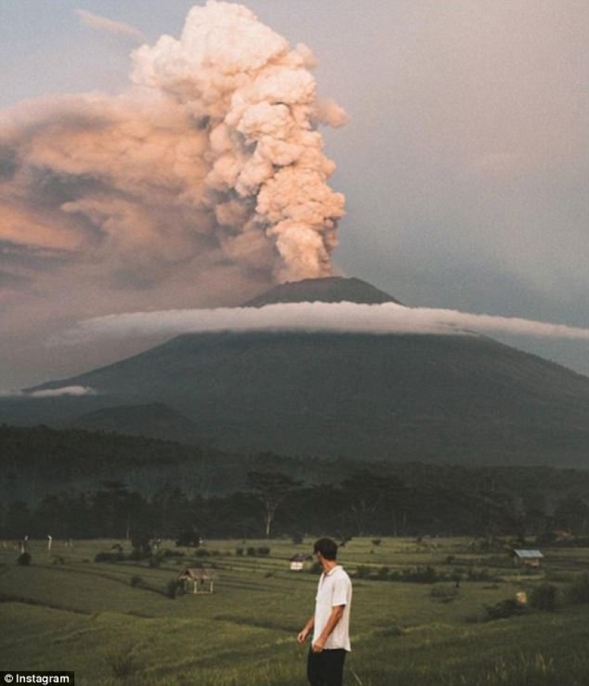 Mientras los residentes de Bali se alejan del volcán, los turistas son fotografiados con el telón de fondo de las emisiones de cenizas Mientras los residentes de Bali se alejan del volcán, los turistas son fotografiados con el telón de fondo de las emisiones de cenizas