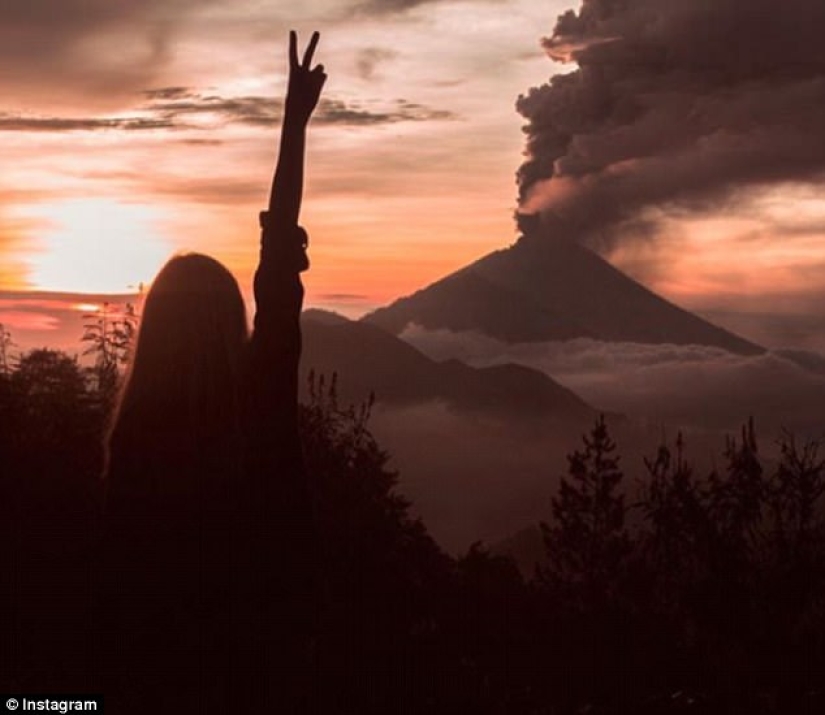 Mientras los residentes de Bali se alejan del volcán, los turistas son fotografiados con el telón de fondo de las emisiones de cenizas Mientras los residentes de Bali se alejan del volcán, los turistas son fotografiados con el telón de fondo de las emisiones de cenizas