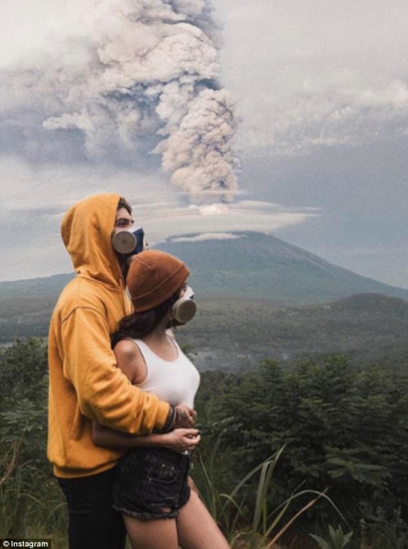 While the residents of Bali are moving away from the volcano, tourists are photographed against the background of ash emissions