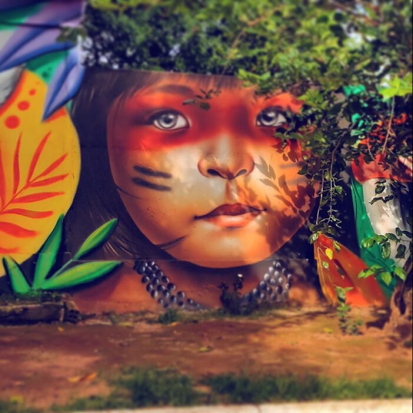 Artista callejero continúa pintando retratos en paredes junto a árboles que también sirven como cabello Artista callejero continúa pintando retratos en paredes junto a árboles que también sirven como cabello
