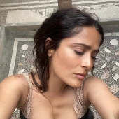 Salma Hayek, 57, is a makeup-free beauty as she eats a strawberry fresh off the vine during trip to 'magical' island in Italy