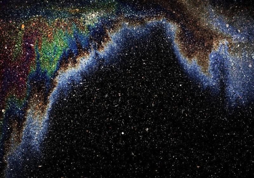 Galaxias y constelaciones ilusorias hechas de gasolina y aceite sobre asfalto