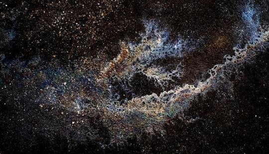 Illusory galaxies and constellations made of gasoline and oil on asphalt