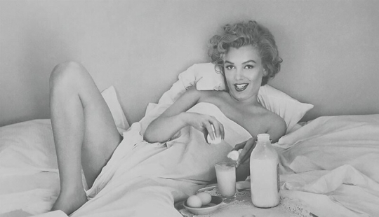 Playful Marilyn Monroe has breakfast in bed