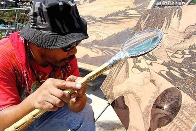 The artist draws with a magnifying glass and sunlight The artist draws with a magnifying glass and sunlight